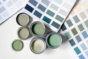 Selection of muted green exterior paint samples in open cans and colour swatches, highlighting the benefits of using muted green exterior paint for home design.