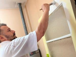 A painter applying paint indoors, paint smell bad due to poor ventilation or low-quality products.