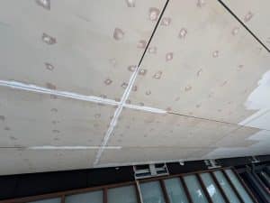 Ceiling with multiple gyprock patches, showing surface preparation for effective patch gyprock repair.