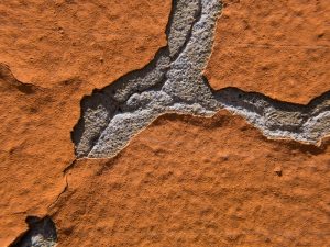 Peeling paint on an exterior wall showing poor paint adhesion, highlighting the importance of proper preparation for durability.