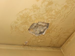 Water damage on a ceiling with plaster cracking and falling away.