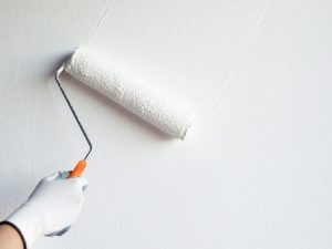 The painter carefully applies paint to the wall to avoid paint spots on the wall and ensure an even finish