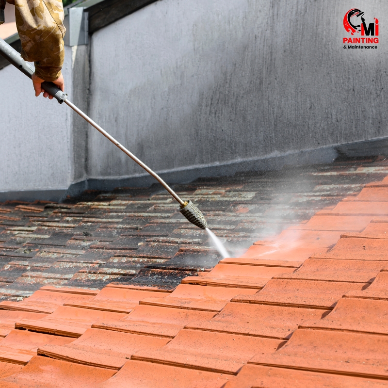 Worker performing concrete pressure cleaning on a sidewalk with a high-pressure hose, removing dirt and grime efficiently.