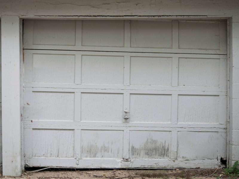 Old white garage door with peeling paint showing need for garage painting.