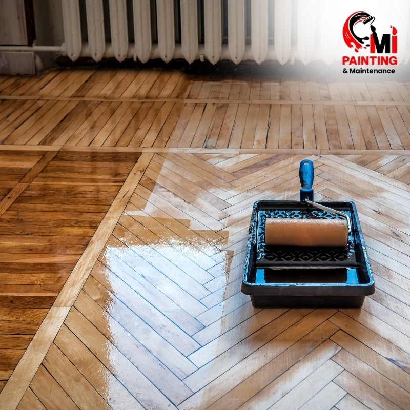 Roller tray with varnish applied on wooden parquet floor.